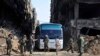 FILE - In this file photo released April 30, 2018 by the Syrian official news agency, SANA, Syrian government forces oversee a bus carrying al-Qaida-linked fighters during an evacuation from the Palestinian refugee camp of Yarmouk, near Damascus, Syria.
