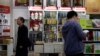 FILE - Customers walk past portraits of Mao Zedong displayed at a bookstore in Beijing. Authorities in China have ordered books by Chinese-American scholar Yu Ying-shih and several others to be removed from sale.