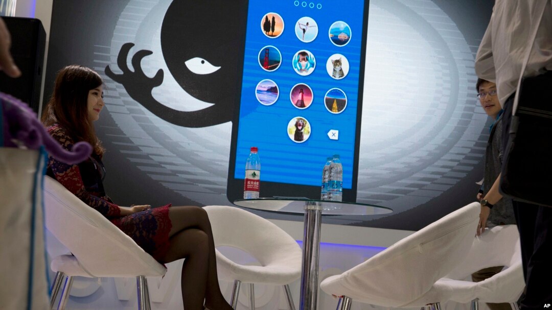 A woman sits near a display showing the dangers of hackers breaking into mobile devices during the Global Mobile Internet Conference in Beijing, China, April 29, 2016.