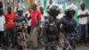 Ugandan riot police stand close to dejected opposition supporters to prevent them from demonstrating, shortly after the election result was announced, in downtown Kampala, Uganda, Feb. 20, 2016. 