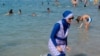 FILE - A woman wearing a burkini walks in the water on a beach in Marseille, France, Aug. 27, 2016. 