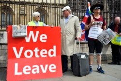 FILE - Pro-Brexit demonstrators hold a placard outside the Houses of Parliament, in London, Sept. 5, 2019.