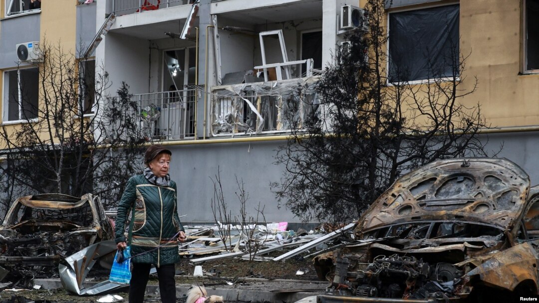 Un residente con un perro camina junto a automóviles destruidos y un edificio de apartamentos dañado por un ataque con aviones no tripulados rusos, en Odesa, Ucrania, el 9 de noviembre de 2024.
