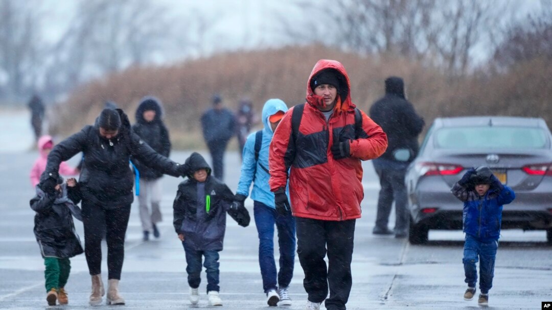 Inmigrantes corren bajo la lluvia hacia las tiendas de campaña en el alojamiento para inmigrantes en Floyd Bennett Field, el martes 9 de enero de 2024, en el distrito de Brooklyn en Nueva York. (Foto AP/Mary Altaffer)