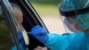 FILE - A health care worker uses a swab to test a man at a coronavirus disease drive-in testing location in Houston, Texas, Aug. 18, 2020. 