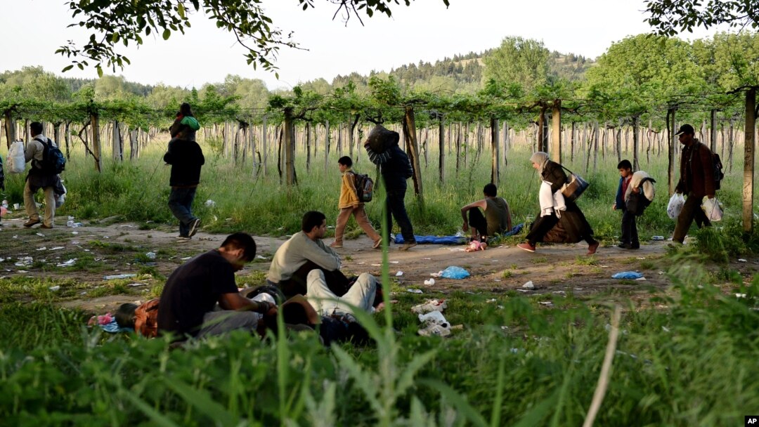FILE - Afghan migrants rest in the open as others pass by after crossing illegally into Macedonia from Greece, near the town of Gevgelija, Macedonia, May 6, 2015.
