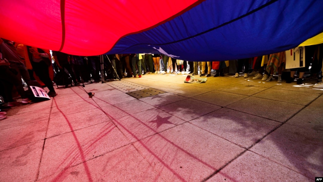 La gente exhibe una bandera venezolana gigante durante una protesta convocada por la oposición venezolana para que se reconozca la "victoria" electoral en el Monumento a la Revolución en la Ciudad de México el 17 de agosto de 2024.