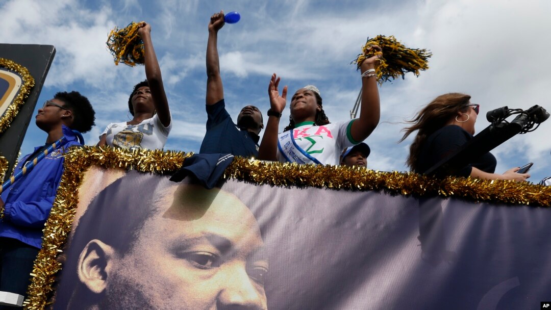People aboard a float from Florida International University wave to crowds during a parade honoring Dr. Martin Luther King Jr. in the Liberty City neighborhood of Miami, Jan. 16, 2017.