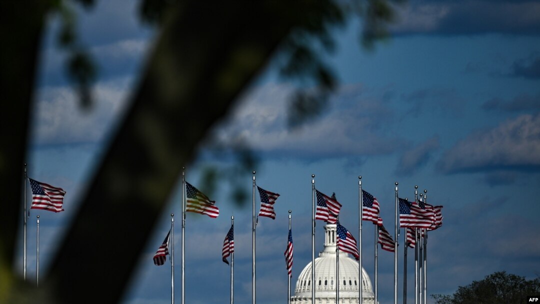 FILE - The dome of the U.S. Capitol building is seen behind a row of U.S. flags in Washington, April 10, 2020.