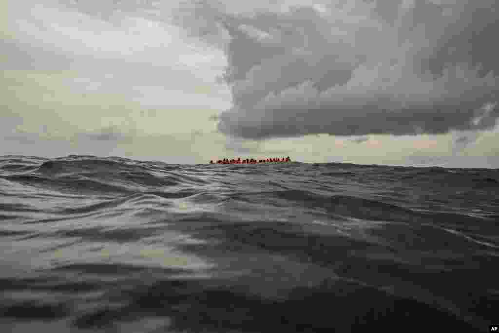Refugees and migrants wait to be rescued by aid workers from the Spanish NGO Proactiva Open Arms, 60 miles north of Al-Khums, Libya, Feb. 18, 2018, after leaving Libya aboard an overcrowded rubber boat in an attempt to reach European soil.