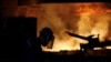 FILE - A worker is silhouetted against a blast furnace at the Chongqing Iron and Steel plant in Changshou, Chongqing, China, Aug. 6, 2018. 