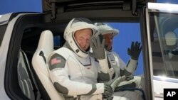 NASA astronauts Douglas Hurley, left, and Robert Behnken, wearing SpaceX spacesuits, depart the Neil A. Armstrong Operations and Checkout Building for Launch Complex 39A during a dress rehearsal prior to the Demo-2 mission launch, May 23, 2020, 