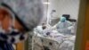 FILE - A physician stands outside a room at an Intensive Care Unit as a nurse suctions the lungs of a COVID-19 patient, April 20, 2020, in Yonkers, New York.