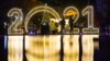 Women walk under an umbrella in front of a 2021 sign displayed in downtown Pristina on December 30, 2020, as Kosovars prepare to celebrate the New Year 2021 at their homes, amid the ongoing Covid-19 (novel coronavirus) pandemic. (Photo by Armend NIMANI / 
