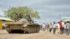 FILE - In this photo provided by the African Union Mission to Somalia (AMISOM), African Union (AU) soldiers from Uganda sit on their tank as residents walk past in the town of Bulomarer, in the Lower Shabelle region of Somalia, Aug. 31, 2014.