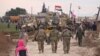 FILE - In this frame grab from video, Russians, Syrians and others gather next to an American military convoy stuck in the village of Khirbet Ammu, east of Qamishli city, Syria, Feb. 12, 2020. 