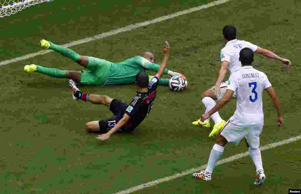 Goalkeeper Tim Howard of the U.S. makes a save as Germany's Thomas Mueller looks on at the Pernambuco arena in Recife, June 26, 2014.