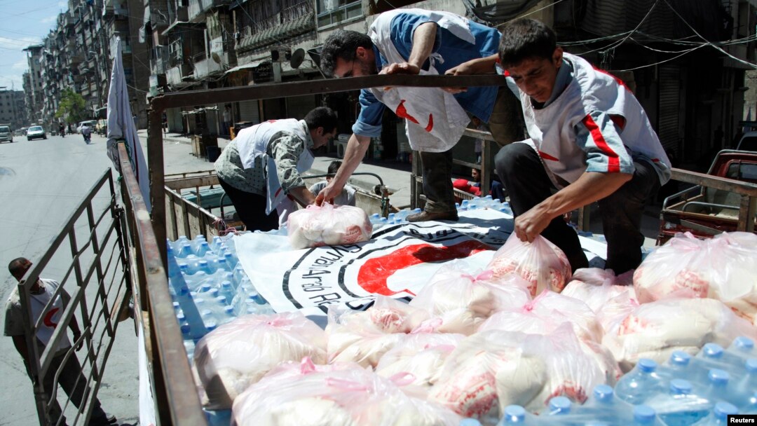 Syrian Arab Red Crescent members place a red crescent flag on top of a food aid truck before moving it to Aleppo Central Prison, May 11, 2014. 