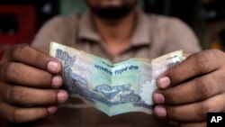 A cashier at an Indian restaurant counts money in New Delhi, India, Thursday, June 13, 2013. 
