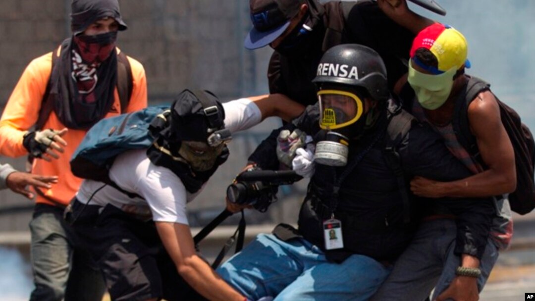 Un periodista es auxiliado por manifestantes durante una protesta antigubernamental en Caracas, Venezuela.