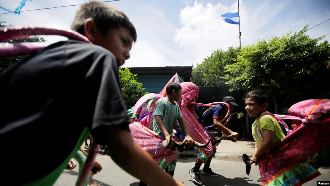 Niños nicaraguenses disfrazados juegan en la calle antes de las festividades en honor del santo patrón de la nación Santo Domingo de Guzmán. Managua, 1 de agosto de 2018.