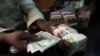 FILE - A trader changes dollars with naira at a currency exchange store in Lagos, Nigeria.