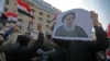FILE - Iraqis carry pictures of the country's top Shi'ite cleric, Grand Ayatollah Ali al-Sistani, as they demonstrate in the capital Baghdad's Tahrir Square, Dec. 5, 2019. 