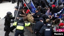 Pro-Trump protesters tear down a barricade as they clash with Capitol Police during a rally to contest the certification of the 2020 U.S. presidential election results by the U.S. Congress, at the U.S. Capitol Building in Washington, Jan. 6, 2021.