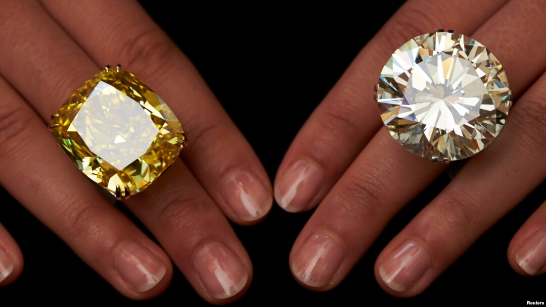 A model poses with a vivid yellow 100.09 carats diamond (L) and a 103.46 carats diamond ring during an auction preview at Sotheby's in Geneva May 7, 2014. These items are expected to reach between CHF 13,250,000 to 22,250,000 (USD 15,000,000 to 25,000,000