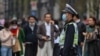 A police officer wearing a face mask monitors pedestrian traffic along a street in Shanghai on October 28, 2020.