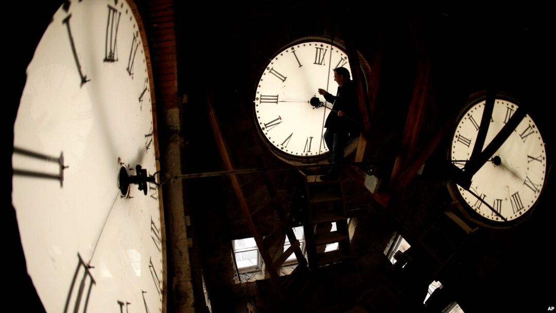 FILE - Custodian Ray Keen inspects a clock face before changing the time on the 100-year-old clock atop the Clay County Courthouse, March 8, 2014, in Clay Center, Kansas. (AP Photo/Charlie Riedel, File)
