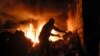 People try to remove car tires from a burning car shop after shelling by Azerbaijan's artillery during a military conflict in Stepanakert, the separatist region of Nagorno-Karabakh, Oct. 23, 2020. 