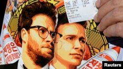 File - Dennis Lavalle holds a ticket and a poster of the film "The Interview" starring actors Seth Rogen and James Franco, Dec. 25, 2014.