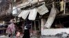 FILE - Iraqis inspect the aftermath a day after a car bomb attack in a shopping area in Karradah, Baghdad, Iraq, Aug. 1, 2012. 