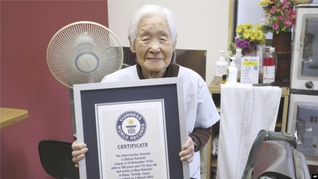 Shitsui Hakoishi, de 108 años, posa con el certificado de Guinness World Records que la reconoce como la barbera más anciana del mundo, en su barbería de Nakagawa, en la prefectura de Tochigi, en el este de Japón, el miércoles 5 de marzo de 2025. AP