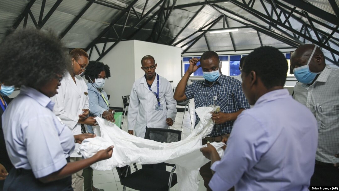 Afisa mkaguzi wa Afya akiwaonyesha madaktari namna ya kutumia vifaa vya kujikinga na virusi vya corona kabla ya madaktari hao wa Hospitali ya Taifa ya Kenyatta ya Nairobi kuelekea katika wadi iliyowekewa karantini ya Hospitali ya Mbagathi, Alhamisi, April2, 2020.AP Photo/Brian).