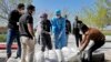 Men, some in protective gear, bury a coronavirus victim at a cemetery outside Tehran, Iran, March 30, 2020.