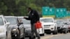 A man with a gas container is greeted by a motorist waiting in a lengthy line to enter a gasoline station during a surge in the demand for fuel following the cyberattack that crippled the Colonial Pipeline, in Durham, North Carolina, May 12, 2021.