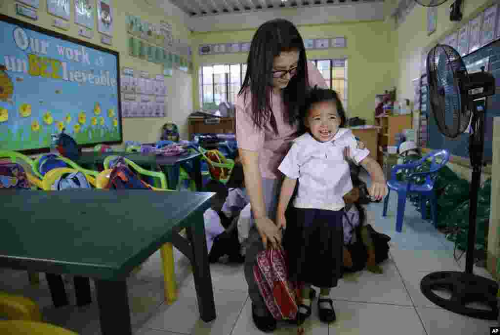 A Filipino teacher tries to prevent a crying student from getting out of the classroom during the first day of school at the President Corazon C. Aquino Elementary School in metropolitan Manila, Philippines.