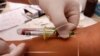 FILE - A health worker takes a blood sample for an HIV test in San Salvador.