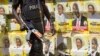 An armed Ugandan riot policeman is seen on patrol against the backdrop of campaign posters for long-time President Yoweri Museveni, as well as local members of Parliament, on a street in Kampala, Uganda, Feb. 17, 2016.