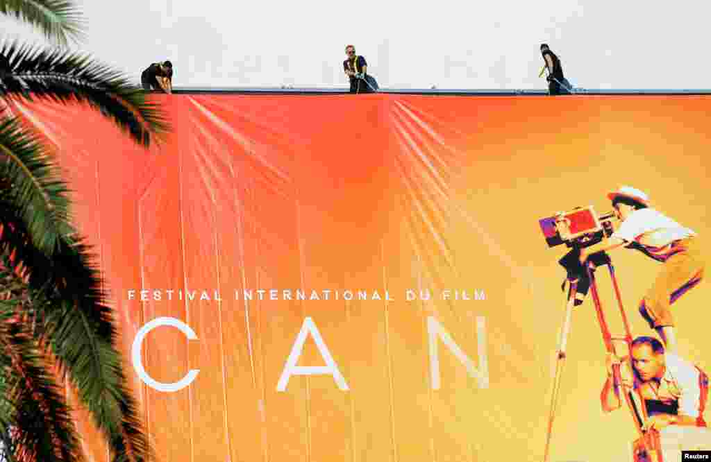 Workers set up a giant canvas of the official poster of the 72nd Cannes Film Festival on the facade of the festival palace in Cannes, France.