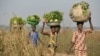 FILE - Women come back from the fields to sell vegetables at a market near the displacement camp close to the airport in Bangui.