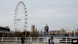 FILE - Women wear face coverings as they walk in London, Friday, Nov. 20, 2020.