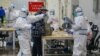 FILE - Medical workers in protective suits receive a patient at the Wuhan International Conference and Exhibition Center, which has been converted into a makeshift hospital to receive patients with mild the coronavirus symptoms, in Wuhan, Feb. 5, 2020.