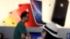 A customer looks at her iPhone in a store of U.S. tech company Apple in Beijing, May 10, 2019. 