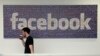 FILE - A Facebook employee walks past a sign at Facebook headquarters in Menlo Park, California, March 15, 2013.