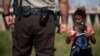 Un migrante de Guatemala le da a beber agua a un bebé mientras espera ser procesado después de entregarse a las autoridades en la frontera entre Estados Unidos y México el 12 de mayo de 2021 en Yuma, Arizona.